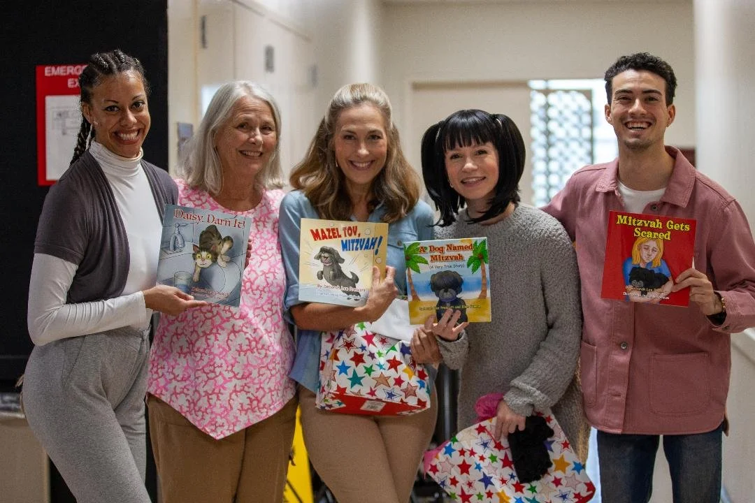 Actors from the play A Mitzvah for Daisy holding Deborah Lee Prescott's books: Daisy Darn It!, Mazel Tov, Mitzvah!, and A Dog Named Mitzvah