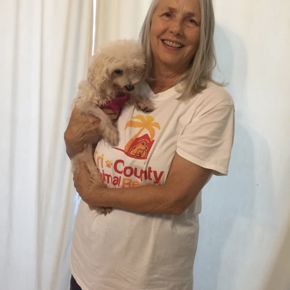 Deborah smiles while holding her newly adopted rescue dog, Sugar, wearing a Tri-County Animal Rescue t-shirt.